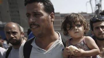 Refugees, mostly from Syria, wait for a bus after disembarking at the port of Piraeus, near Athens, Greece.