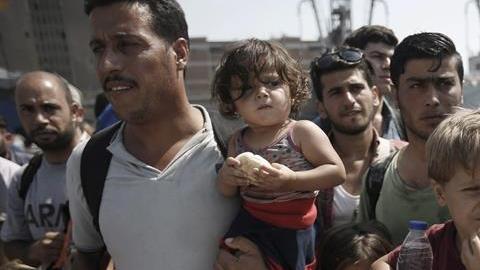 Refugees, mostly from Syria, wait for a bus after disembarking at the port of Piraeus, near Athens, Greece.