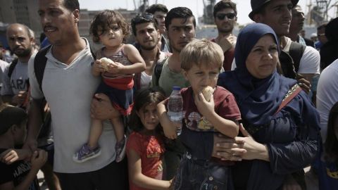 Refugees, mostly from Syria, wait for a bus after disembarking at the port of Piraeus, near Athens, Greece.