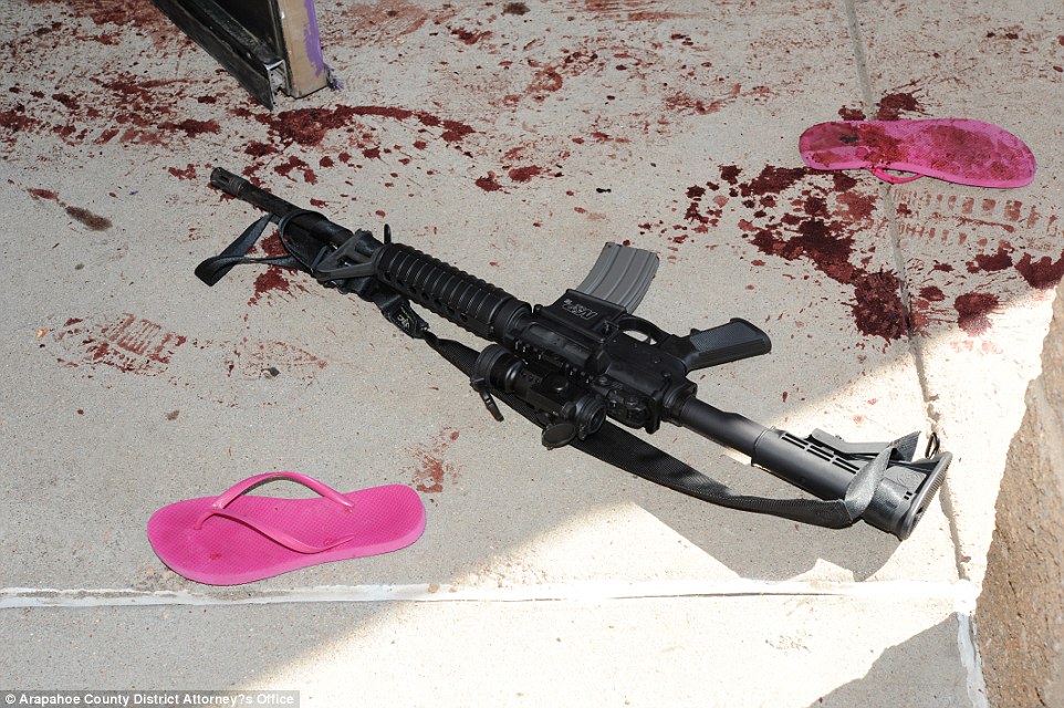 El rifle de Holmes en el suelo afuera del cine, al lado de unas sandalias rosadas, cubiertas de sangre.