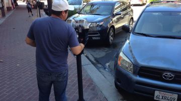 Un inmigrante pone monedas en un parquímetro en la Calle Cuarta de Santa Ana