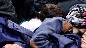 Un niño duerme entre otros refugiados en Victoria Square, Atenas, Grecia.