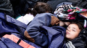 Un niño duerme entre otros refugiados en Victoria Square, Atenas, Grecia.