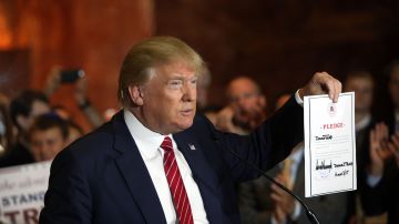 El magnate Donald Trump muestra el documento en el que se compromete a apoyar al candidato republicano que obtenga la nominación de su partido para buscan la presidencia de EEUU.