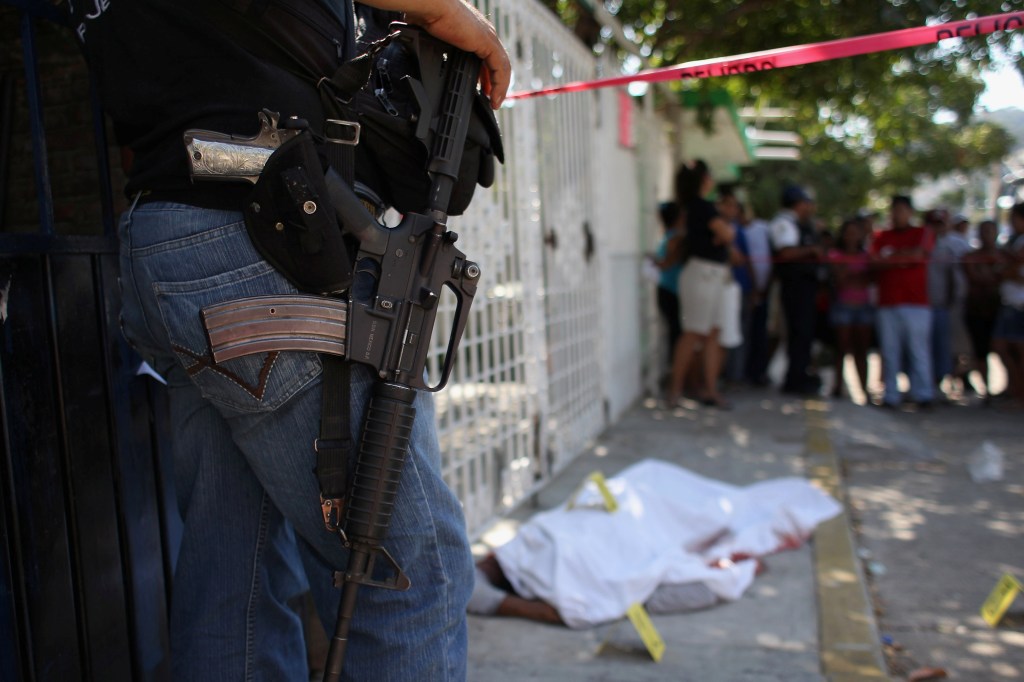 Un policía observa la escena de un crimen relacionado al narcotráfico en Acapulco en el 2012. / Getty
