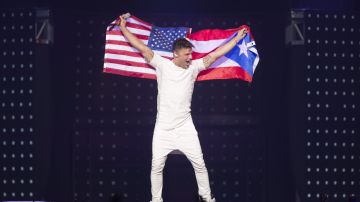 Ricky Martin se abraza a las dos banderas, la de Puerto Rico y Estados Unidos durante el concierto de su gira One World Tour 2015 en Orlando.