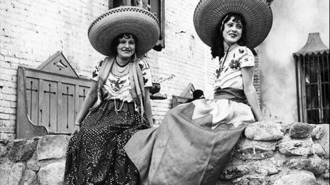 Danzantes descansan postradas sobre una barda en la calle Olvera en 1930.