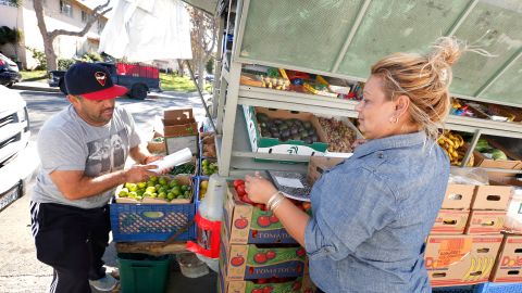 11/04/15 /LOS ANGELES/Ramona Gardens resident Irma Vasquez (R), assisted by Ismael Herrera, purchases cucumbers at Don TrinoÕs produce truck.  Jose Trinidad Herrera, know to the community as Don Trino, has been selling fresh vegetables at Ramona Gardens for more than 20 years and for many residents his truck in the only fresh produce they can purchase for miles. (Photo by Aurelia Ventura/La Opinion)