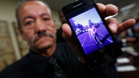 El padre muestra una foto familiar de su hijo, que él cree murió a consecuencias de las descargas eléctricas que le propinaron los agentes del Sheriff. / AURELIA VENTURA