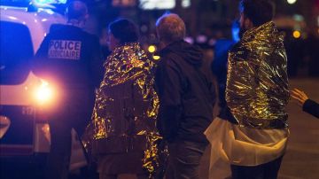 Dos personas son escoltadas por la policía francesa junto a la discoteca Bataclan.