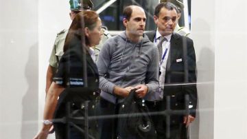 El expresidente de la Asociación Nacional de Fútbol Profesional de Chile, Sergio Jadue (c), en el aeropuerto de Santiago escoltado por la policía para abordar un avión rumbo a Miami junto a su familia.