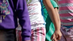 Familias y niños migrantes caminan en línea en el Centro de Detención de la Patrulla Fronteriza en Brownsville, Texas.