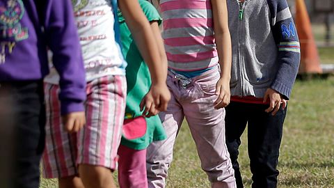 Familias y niños migrantes caminan en línea en el Centro de Detención de la Patrulla Fronteriza en Brownsville, Texas.