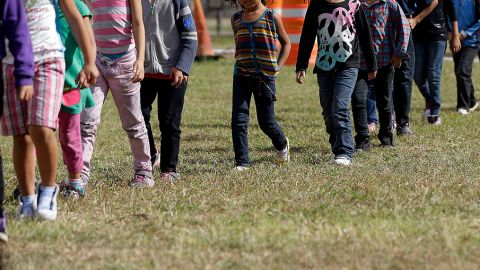 Familias y niños migrantes caminan en línea en el Centro de Detención de la Patrulla Fronteriza en Brownsville, Texas.