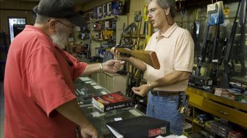 Un propietario de la tienda de armas vende un producto a un cliente.