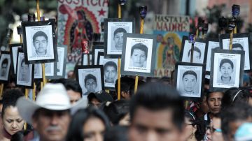 Personas sostienen carteles y fotografías de los 43 estudiantes, en una marcha del Zócalo a la basílica de Guadalupe, en Ciudad de México, donde se celebró una misa para recordar a los desaparecidos del país.