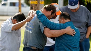Un grupo de hombres se abrazan afuera del Inland Resource Center en San Bernardino, donde una pareja armada ultimó a 14 personas e hirió a muchas más.