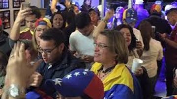 Lilian Tintori (i), esposa del líder opositor venezolano encarcelado Leopoldo López, levanta la mano de Enrique Marquez, miembro del comité ejecutivo del comando de campaña y diputado electo.