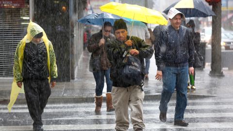 Personas intentan protegerse de la fuerte lluvia en el centro de Los Ángeles. / AURELIA VENTURA