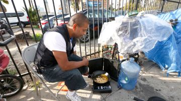 Mark Hermosillo, un desamparado, prepara su almuerzo en un campamento de indigentes cerca de la esquina de las calles Wilshire y Hoover en el centro de Los Ángeles. (Aurelia Ventura/La Opinion)
