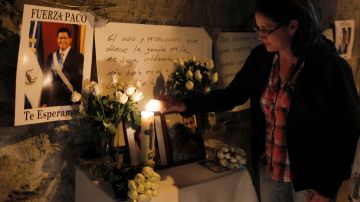 Una salvadoreña enciende una vela a las afueras del hospital donde falleció el expresidente salvadoreño Francisco Flores a los 56 años de edad,