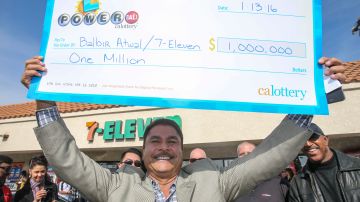 Balbir Atwal, dueño de la tienda donde se vendió el boleto ganador en Chino Hills levanta su enorme cheque por un millón de dólares. /GETTY IMAGES