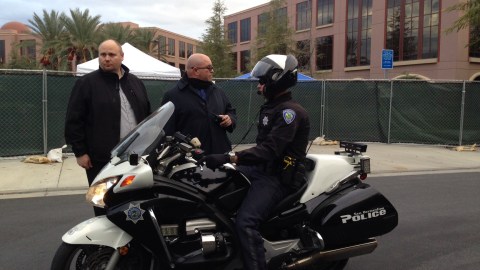 Un policía en moto conversa con guardias privados afuera del Centro Regional Inland de San Bernardino.