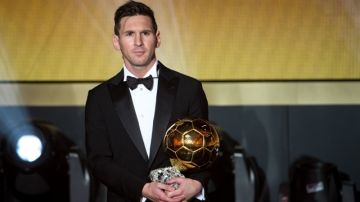 Leonel Messi carga su trofeo del Balón de Oro.