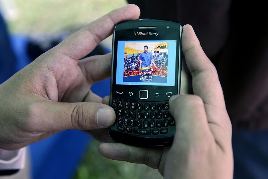 A man uses the new application for mobile phones of Venezuelan opposition candidate, Henrique Capriles Radonski, in Caracas on August 14, 2012. AFP PHOTO/Leo RAMIREZ        (Photo credit should read LEO RAMIREZ/AFP/GettyImages)