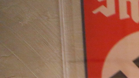 Robert Clary, un sobreviviente del holocausto, posa junto a un afiche Nazi que es parte de la exhibición en la biblioteca. / (Foto: Aurelia Ventura/La Opinion)