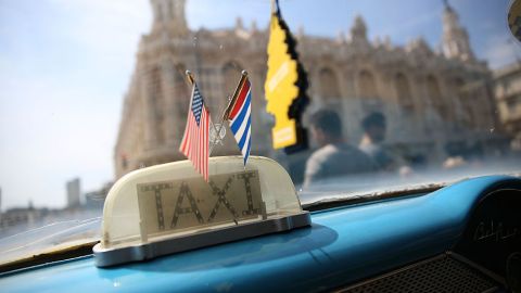 Las banderas de Cuba y Estados Unidos ondean en el interior de un taxi en La Habana.