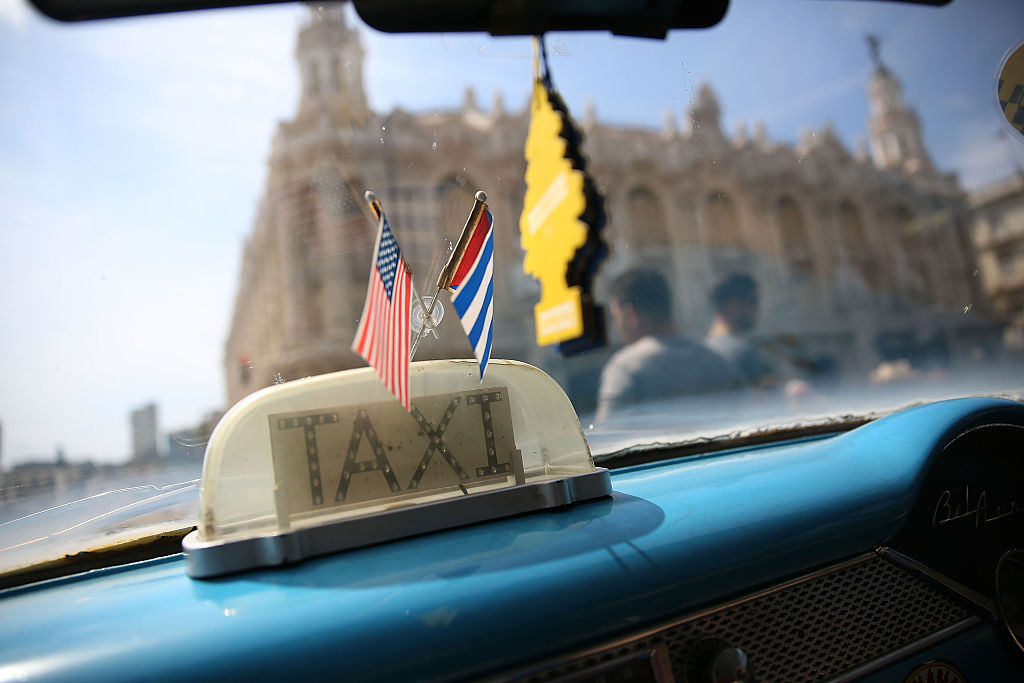 Las banderas de Cuba y Estados Unidos ondean en el interior de un taxi en La Habana.