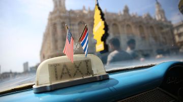 Las banderas de Cuba y Estados Unidos ondean en el interior de un taxi en La Habana.