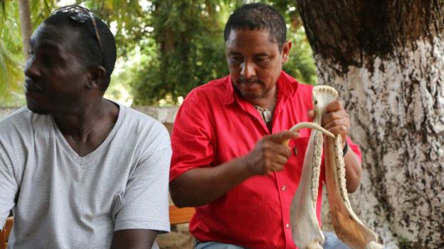 Chogo "El Bandeño" (der.) toca la quijada, un instrumento de origen africano que acompaña su música.
