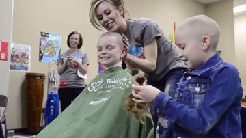Marlee Pack, la niña diagnosticada con cáncer, sostiene el pelo de una de sus compañeras.