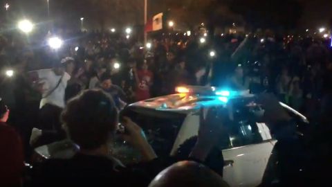 Manifestantes rodearon una patrulla y empezaron a romper las ventanas y saltar sobre el auto.