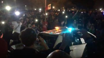 Manifestantes rodearon una patrulla y empezaron a romper las ventanas y saltar sobre el auto.