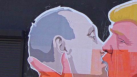 Una mujer pasa junto a un mural en un restaurante que representa al candidato presidencial Donald Trump y el presidente ruso, Vladimir Putin, que se saludan con un beso en Vilnius, Lituania.