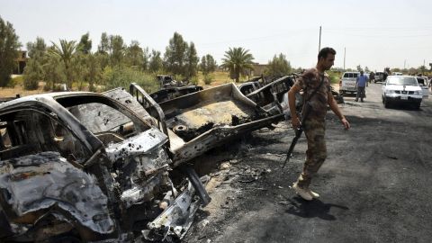 Un soldado iraquí inspecciona varios camiones de ISIS calcinados tras un fuerte enfrentamiento en el sudoeste de Faluya (Irak).