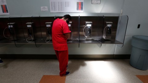 Un inmigrante utiliza un teléfono en el centro de detención de Adelanto, California. (Aurelia Ventura/La Opinion)
