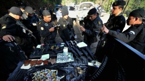 Policías en Guatemala observan un arsenal decomisado al cartel de Los Zetas.