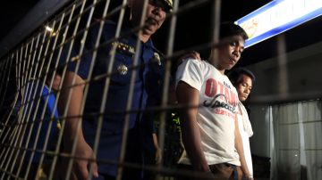 En la imagen, un policía vigila a delincuentes detenidos en Manila en operaciones antidrogas.