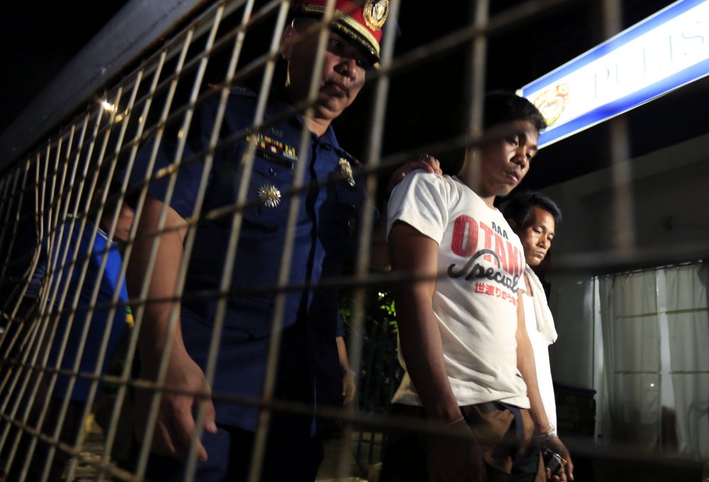 En la imagen, un policía vigila a delincuentes detenidos en Manila en operaciones antidrogas.