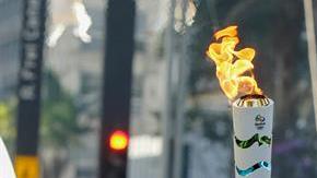 El atleta de tiro con arco de Brasil, Marcos Vinicius, sostiene la antorcha olímpica.