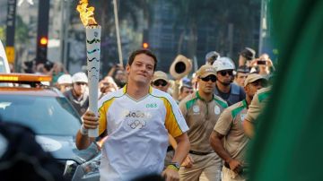 El atleta de tiro con arco de Brasil, Marcos Vinicius, sostiene la antorcha olímpica.