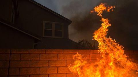 Las llamas cubren la pared de una casa en Santa Clarita, California. Foto: DAVID MCNEW/AFP/Getty Images