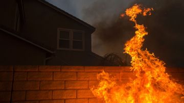 Las llamas cubren la pared de una casa en Santa Clarita, California. Foto: DAVID MCNEW/AFP/Getty Images