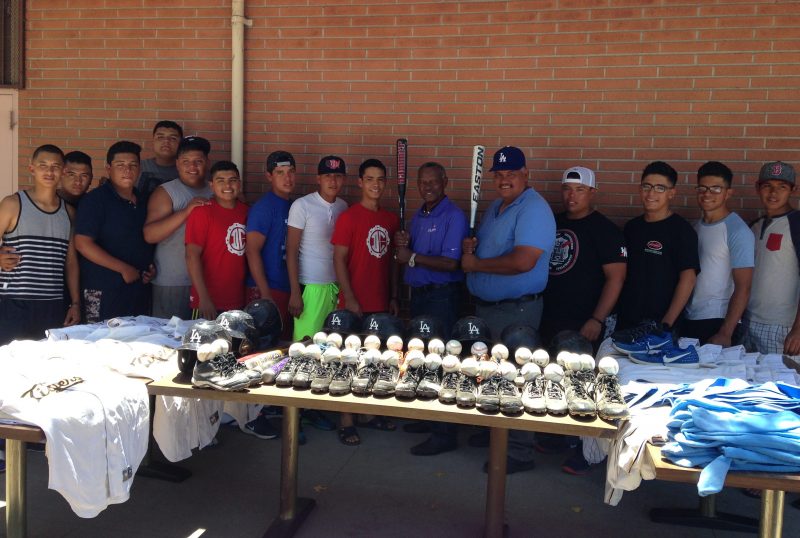 Manny Mota, el mánager José de Jesús García y jugadores de los Abejorros posan con los implementos deportivos donados por el coach de los Dodgers.