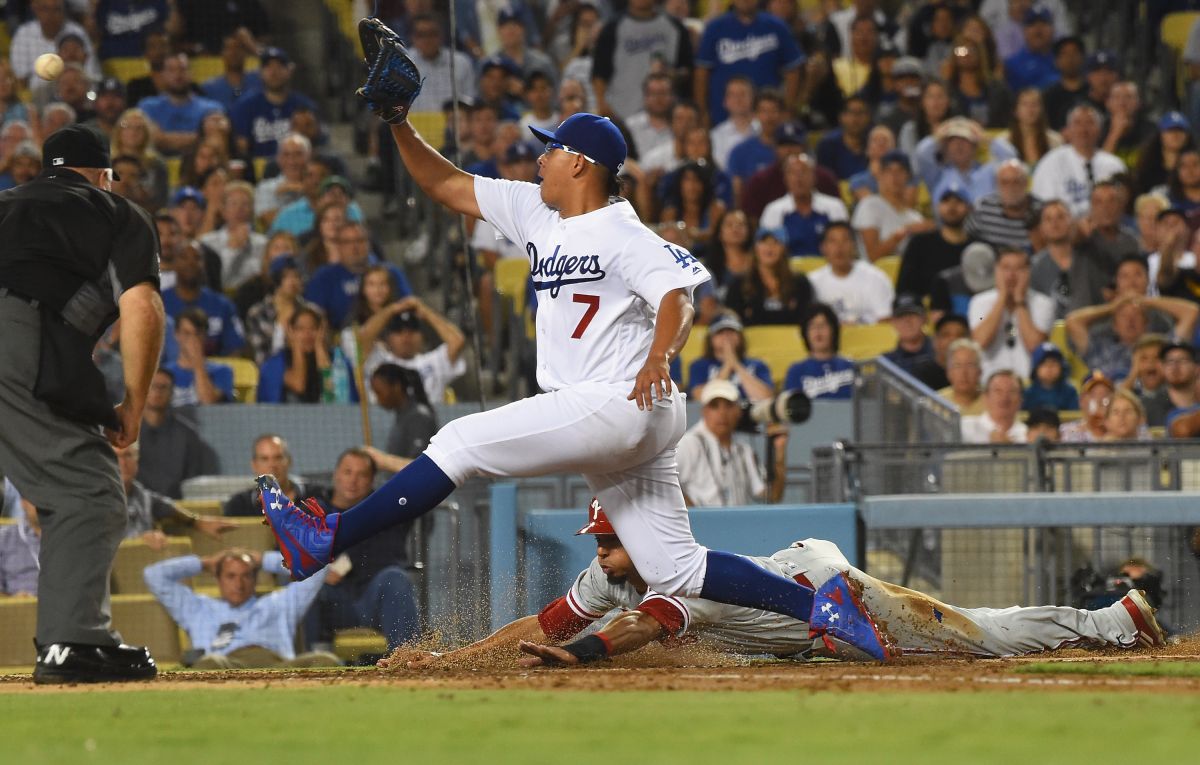 Julio Urías no puede impedir la carrera de Aaron Altherr, de los Filis, tras un error del pitcher de los Dodgers en la tercera entrada.