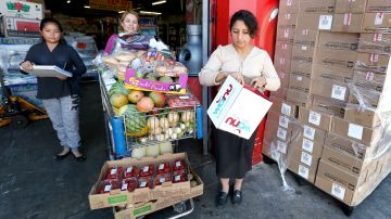 Elfega Barajas (derecha), residente de South Gate, recibe ayuda de Graciela Sanchez mientras consiguen alimentos en el banco de comida World Harvest. (Aurelia Ventura/ La Opinion)